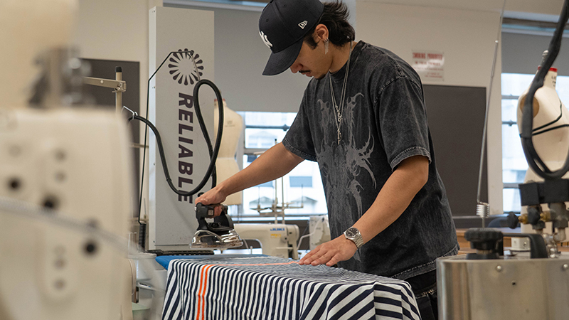 Student ironing fabric in class