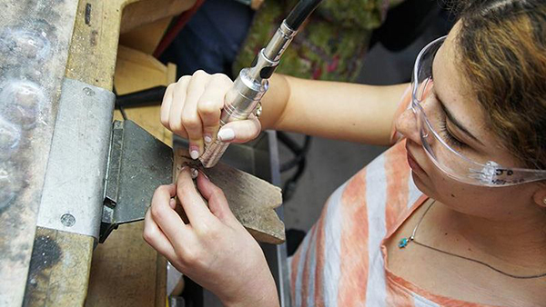 student working on a piece of jewelry in the studio
