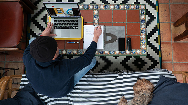 person working on laptop with dog next to them